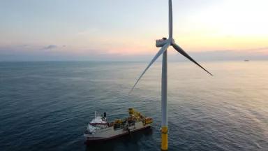 An aerial view of an installation vessel beside a 6-megawatt wind turbine at Coastal Virginia Offshore Wind (CVOW), an offshore wind energy project located approx. 27 miles off the coast of Virginia Beach, Virginia, at sunset on June 24, 2020.