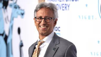 Manish Bapna, smiling, in a gray suit and yellow tie, at the New York NRDC Night of Comedy