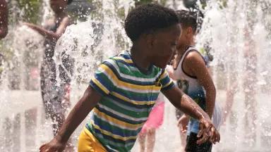Two young children playing in sprinklers in Domino Park, Williamsburg, Brooklyn, New York