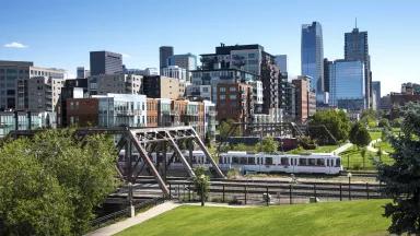 A cityscape view of the lower downtown district of Denver, with the light rail train in the forefront