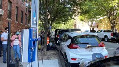 A white passenger electric vehicle being charged at an EV charging station on a street in Bronx, New York City