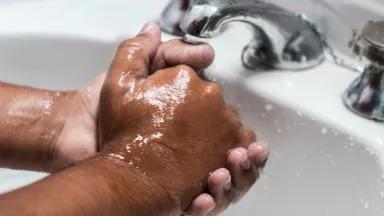 Handwashing under a bathroom water faucet
