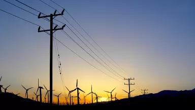 Power lines and a wind farm stand in front of a sunset in Palm Springs, California