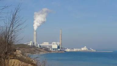 A coal plant sits alongside Lake Michigan in Wisconsin, with a smoke stack releasing emissions.