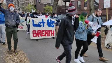 People march down the street holding signs that read "let us breathe" and "stop General Iron."