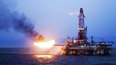 Flames shoot out from the side of an offshore oil rig