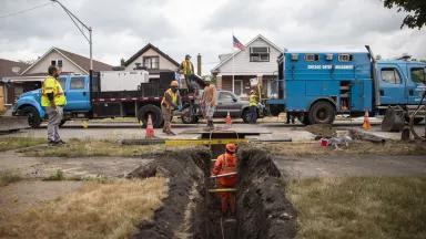 A construction crew working around a ditch dug during replacement of a lead service line outside a Chicago home