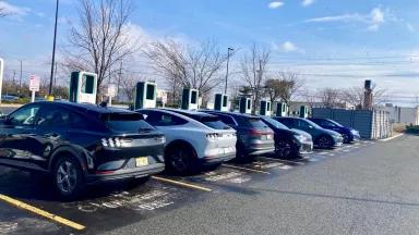 Electric vehicles lined up in front of chargers in a parking lot
