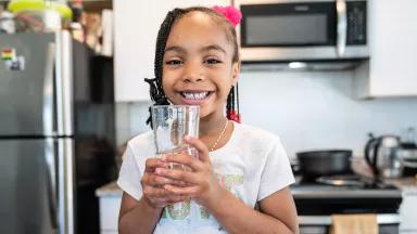 Liyah Watkins, 5, drinking from a glass of water in the kitchen of her home in Washington, DC