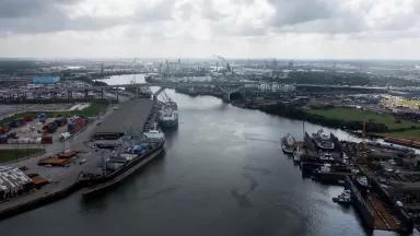 A narrow waterway with ports and industrial facilities lining the banks on both sides