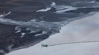 An aerial view of a coastline with a barrier on the water