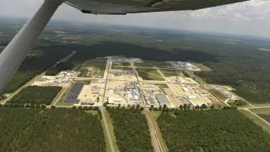 An aerial view of an area of factories, surrounded by forests