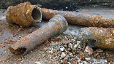 Rusty water pipes sit broken after being pulled up from underground
