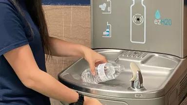 A student refills a water bottle at a school water fountain