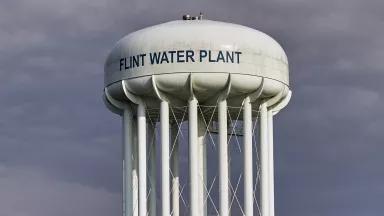 A large white water tower is painted with the words "Flint water plant"