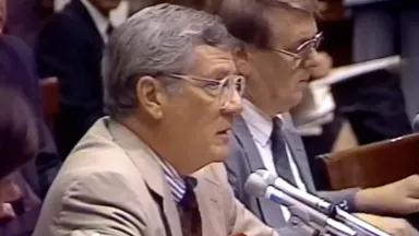 A man sits and speaks into a microphone