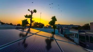 The sun sets over a building with solar panels on its roof 