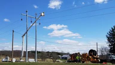 A crew using a cherry picker to work on overhead power lines in rural Ohio