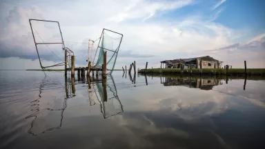 Fishing nets and an abandoned building on eroded and flooded marshland in Louisiana
