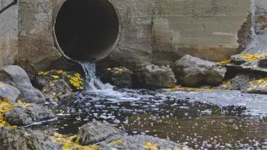 Water from an overflow pipe running into a stream.