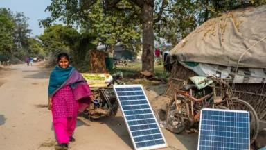 Photo of a woman in a rural area of India with portable solar panels.