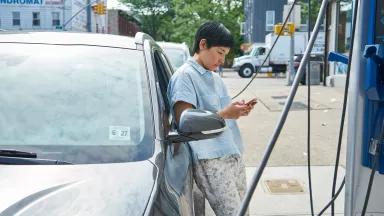 A woman charging her electric car at a public charging station in Brooklyn, New York City.