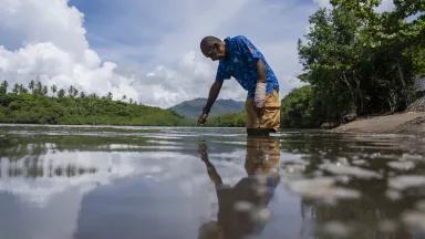 Sailosi Ramatu touches the water in the place where his house used to stand at the old village site in Vunidogoloa, Vanua Levu, Fiji, on March 25, 2025.

Ramatu's home was destroyed by flooding caused by sea level rise, storm surge and high tides. Many people in the village relied on fishing for their livelihoods, so the move inland to higher ground required many fishermen learn to become farmers, a change that initially proved challenging.