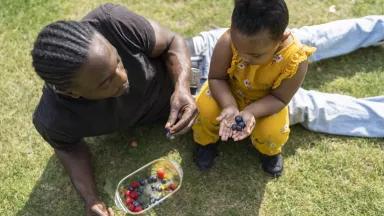 A father and his daughter snacking on fresh berries.