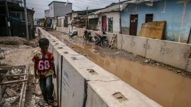 A young boy walking by the tidal flood mitigation embankment project under construction in Muara Angke, Jakarta, Indonesia, on January 6, 2026.The Jakarta Provincial Government accelerated the construction of the 1,390-meter embankment to mitigate tidal flooding caused by land subsidence in the area. 