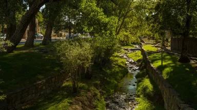 A small section of river flows near stone walls in a park