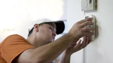 A homeowner installing a programmable thermostat