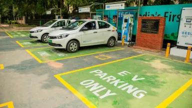 Two electric vehicles charge in an EV charging lot in India