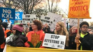A crowd of people holding signs to stop the Keystone XL pipeline