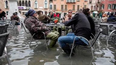 cafe patrons sitting in floodwaters in Venice, Italy