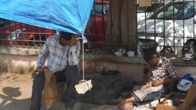 A man in Ahmedabad, Gujarat has his hand to his head as he works under a makeshift shelter to escape the heat