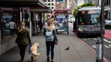 Women walking down a street with cars and and bus