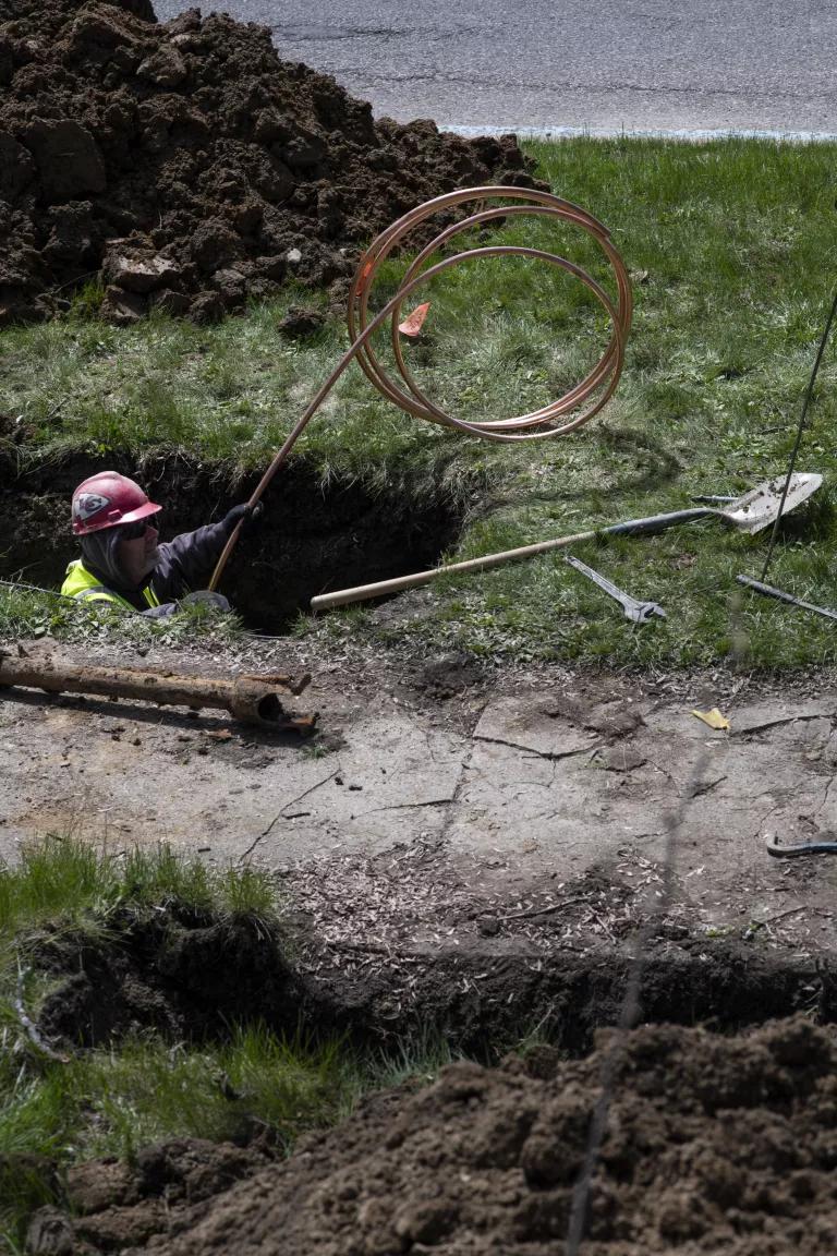 A worker in a hole in the ground with a copper wires