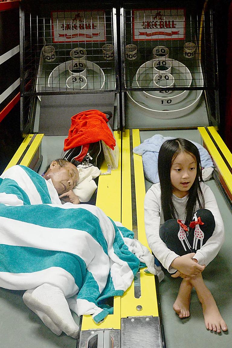 A man and young child rest on platforms of arcade games