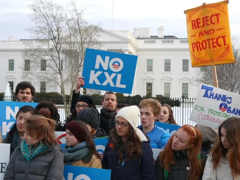Protesters march in front of the White House, some holding posters that read, "No KXL"